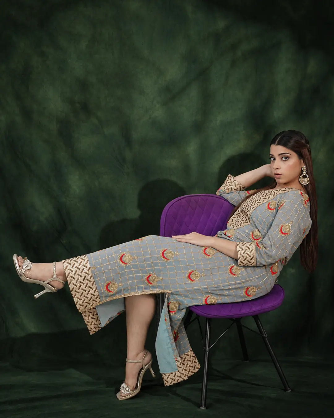 Seated model wearing grey long dress with gold embroidery